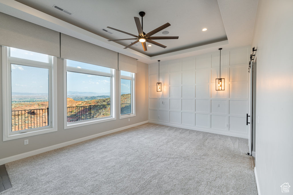 Carpeted empty room with a raised ceiling and ceiling fan