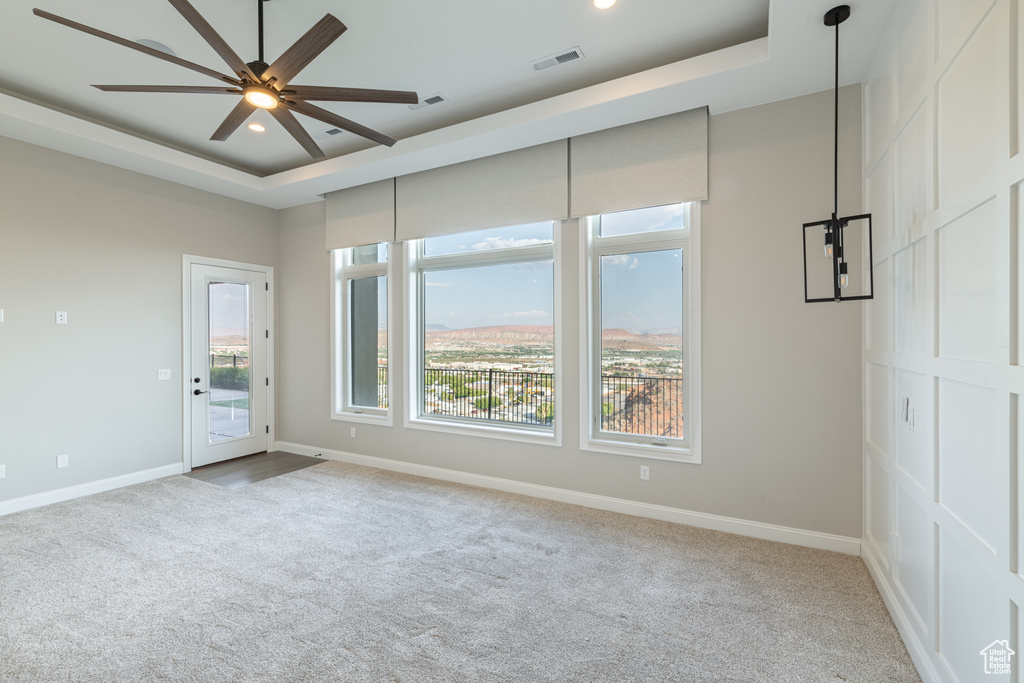 Unfurnished bedroom with light colored carpet, access to outside, and a tray ceiling