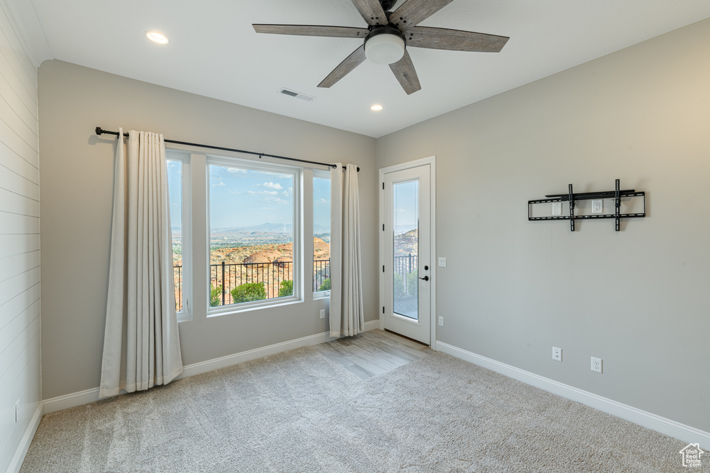 Spare room featuring ceiling fan, a wealth of natural light, and light colored carpet