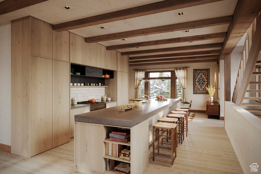 Kitchen with decorative backsplash, beam ceiling, light hardwood / wood-style flooring, range with gas cooktop, and a kitchen island with sink