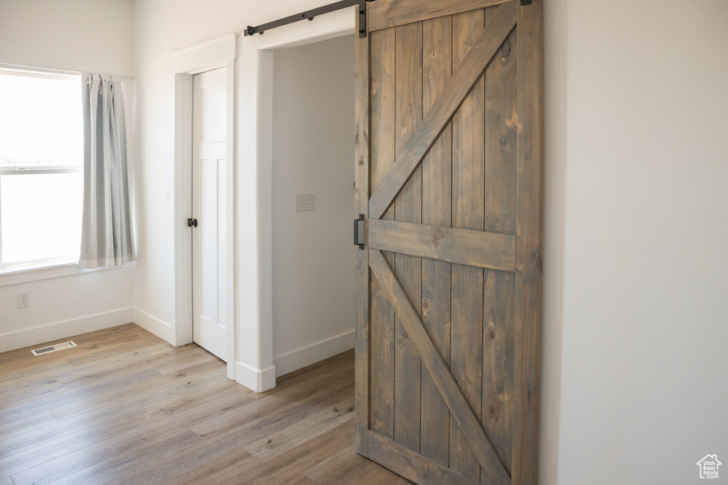 Hall with a barn door and light wood finished floors