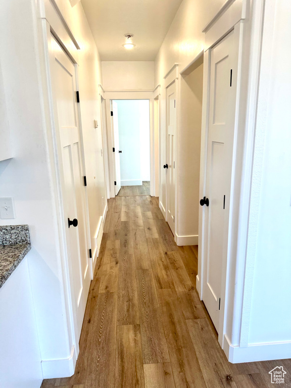 Hallway with light wood-style floors and baseboards