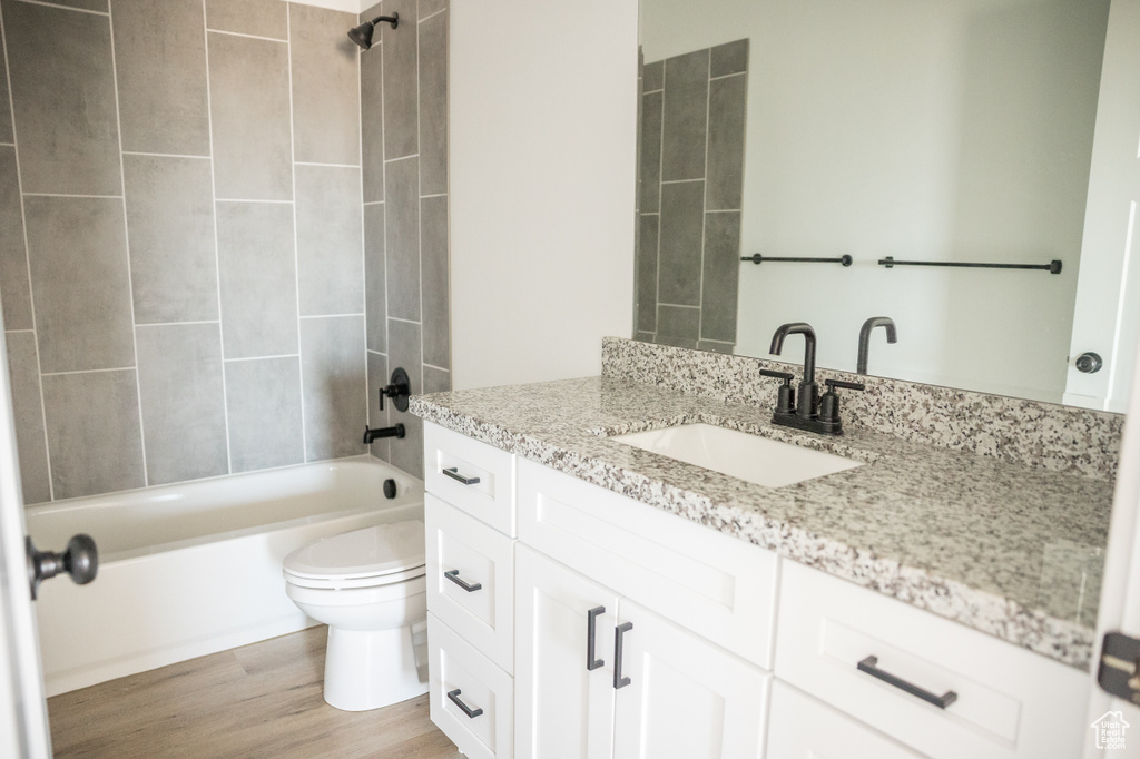 Full bath featuring vanity,  shower combination, and wood finished floors