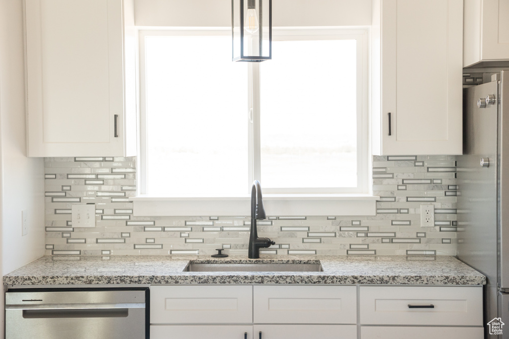 Kitchen featuring appliances with stainless steel finishes, backsplash, white cabinets, and healthy amount of natural light