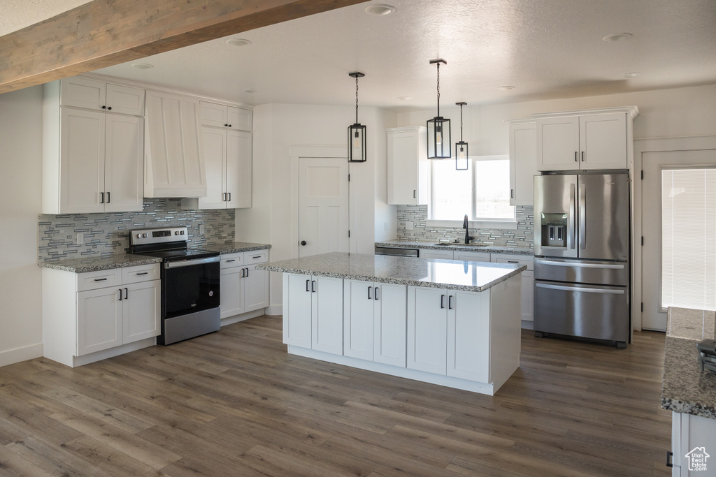 Kitchen with stainless steel appliances, backsplash, white cabinets, a kitchen island, and recessed lighting
