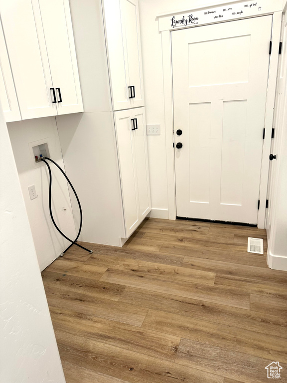 Washroom featuring cabinet space, light wood finished floors, and hookup for a washing machine