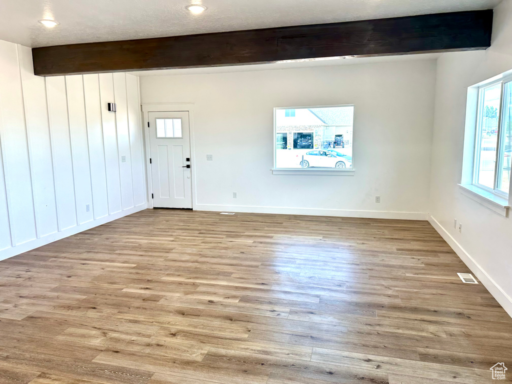 Foyer featuring beamed ceiling, healthy amount of natural light, and wood finished floors