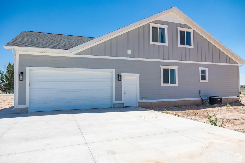 View of front of home with board and batten siding, a garage, concrete driveway, and a shingled roof