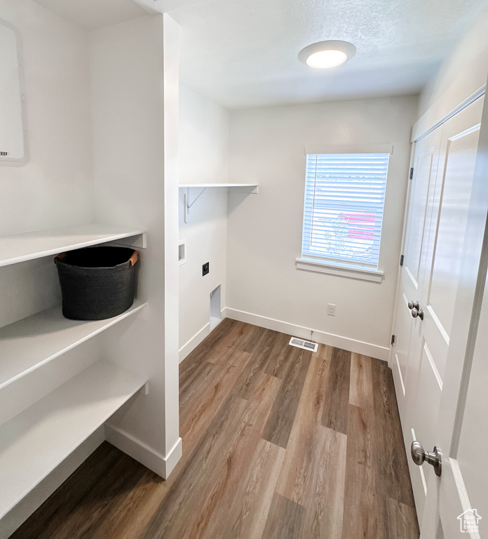 Washroom with electric dryer hookup and hardwood / wood-style flooring