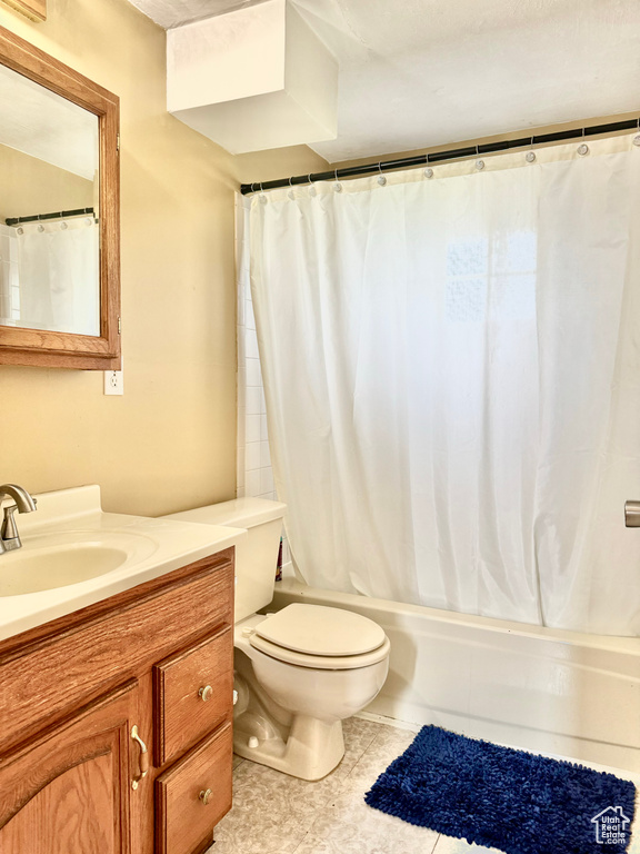 Full bathroom featuring shower / tub combo with curtain, vanity, tile patterned floors, and toilet