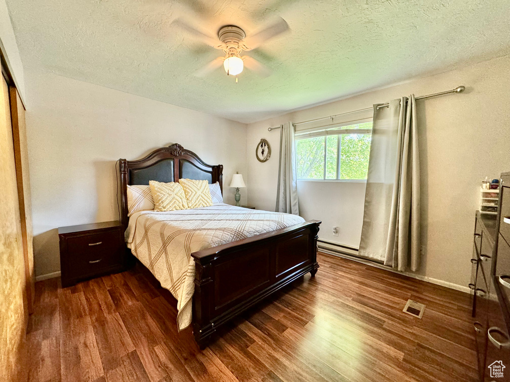 Bedroom featuring a textured ceiling, a closet, wood-type flooring, and ceiling fan
