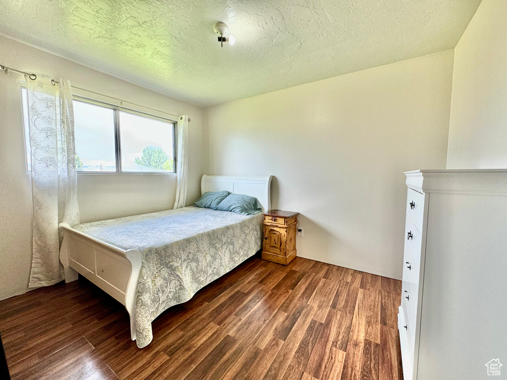 Bedroom featuring a textured ceiling and dark hardwood / wood-style floors