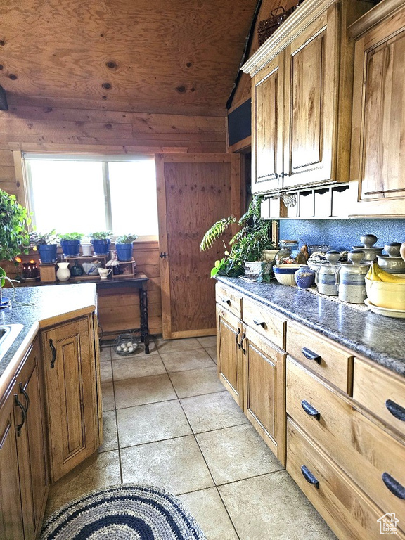 Kitchen with lofted ceiling, wood walls, light tile patterned floors, and wood ceiling