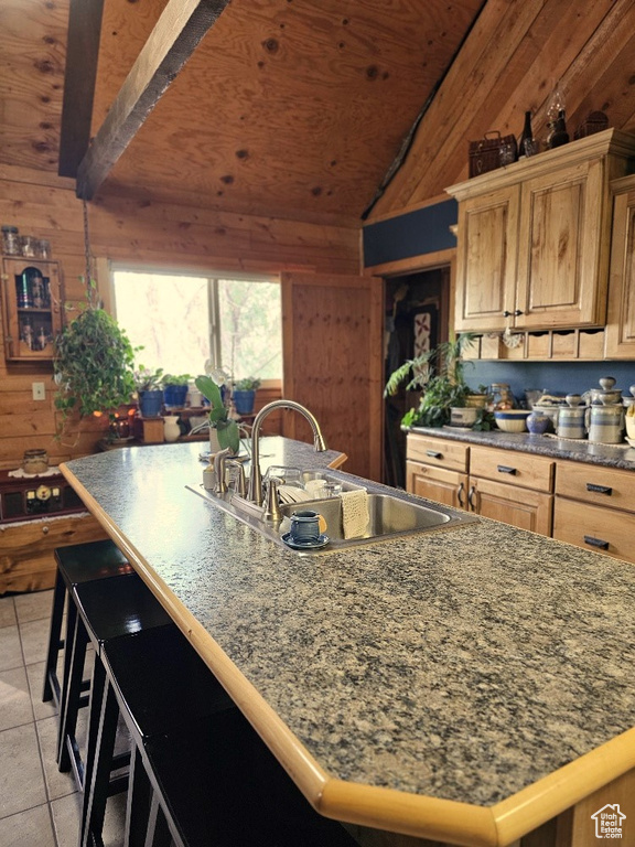 Kitchen with wooden walls, light tile patterned floors, sink, and lofted ceiling