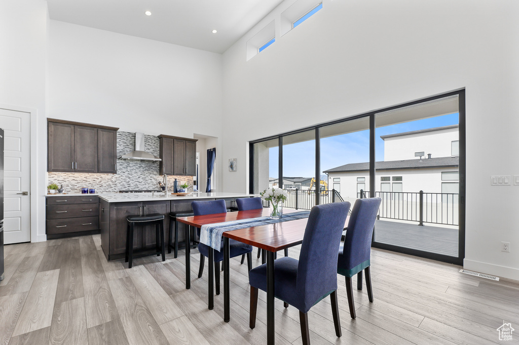 Dining space with light hardwood / wood-style flooring and a high ceiling