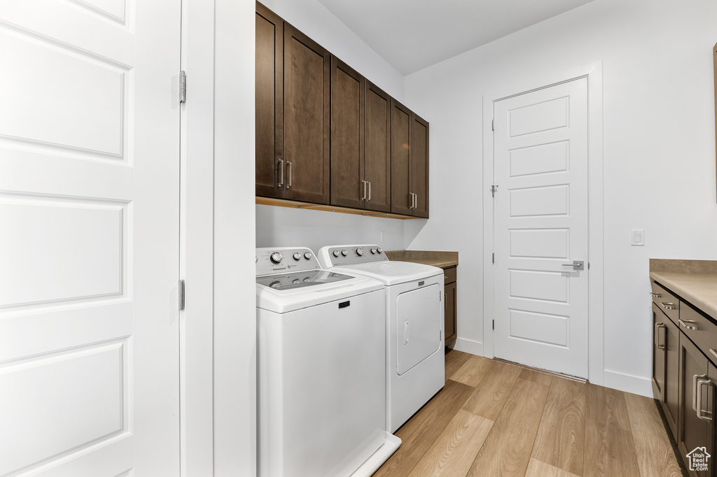 Laundry area featuring separate washer and dryer, cabinets, and light wood-type flooring