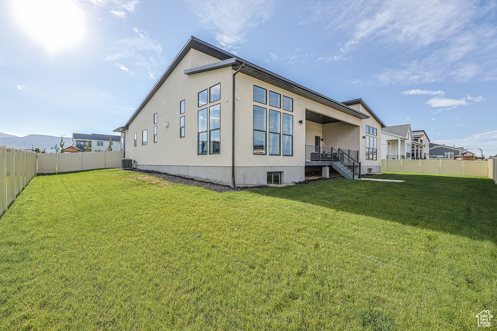 View of property exterior featuring central AC and a lawn