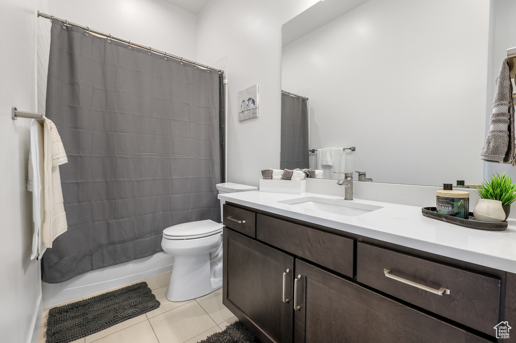 Full bathroom with shower / bath combo with shower curtain, vanity, tile patterned floors, and toilet