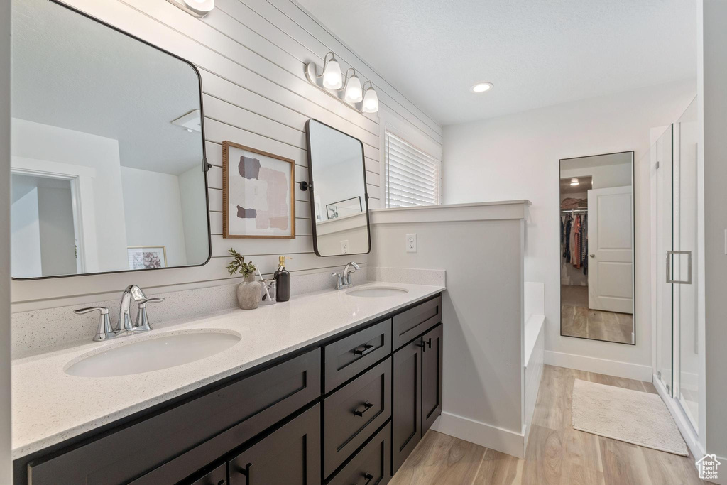 Bathroom featuring plus walk in shower, wood-type flooring, and double vanity