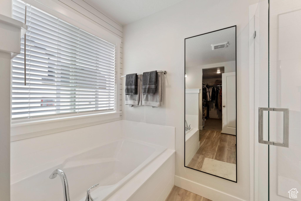 Bathroom with shower with separate bathtub and wood-type flooring