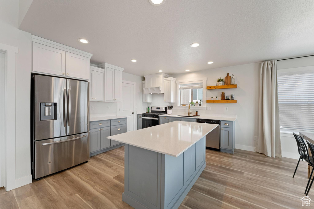 Kitchen with light hardwood / wood-style flooring, stainless steel appliances, gray cabinetry, sink, and a kitchen island