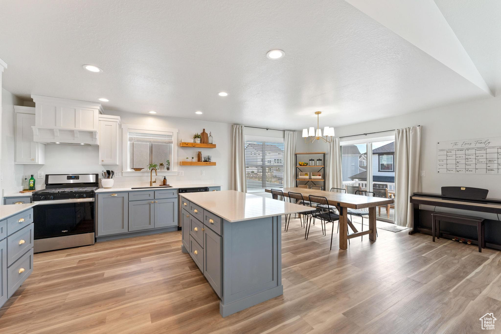 Kitchen featuring white cabinetry, a chandelier, sink, stainless steel range, and light hardwood / wood-style floors