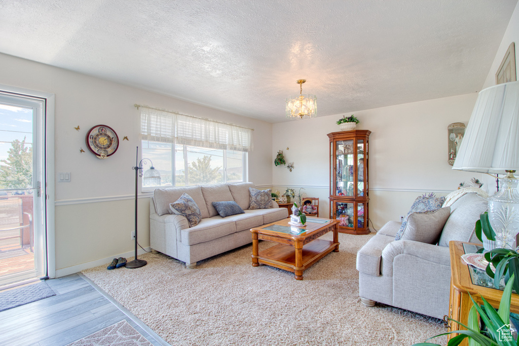 Living room featuring light hardwood / wood-style floors, a textured ceiling, and an inviting chandelier