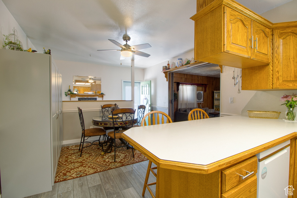 Kitchen with kitchen peninsula, light wood-type flooring, and ceiling fan