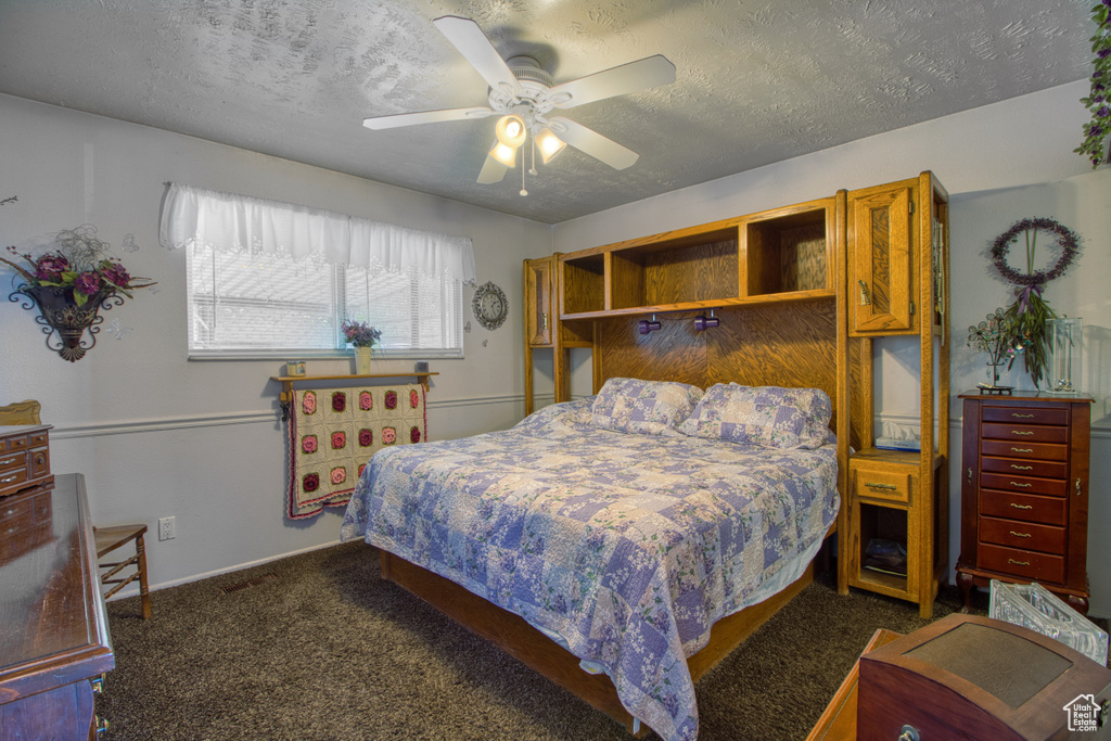 Bedroom featuring dark colored carpet, a textured ceiling, and ceiling fan