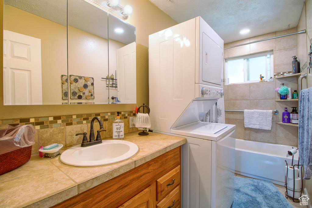 Bathroom with backsplash, a bathing tub, vanity, and a textured ceiling