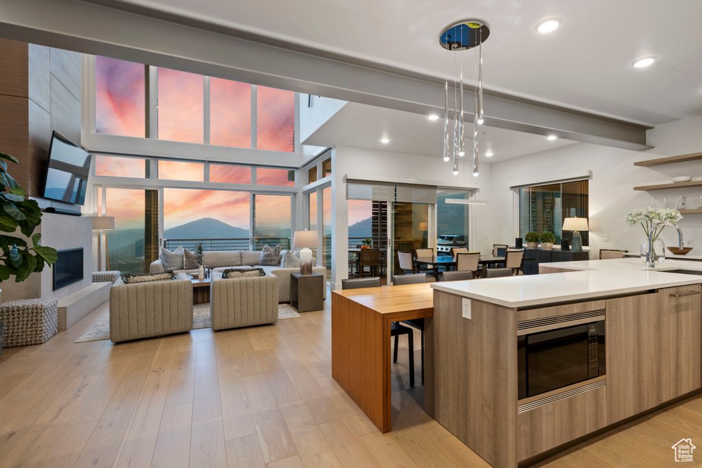 Kitchen with light hardwood / wood-style floors, hanging light fixtures, and sink