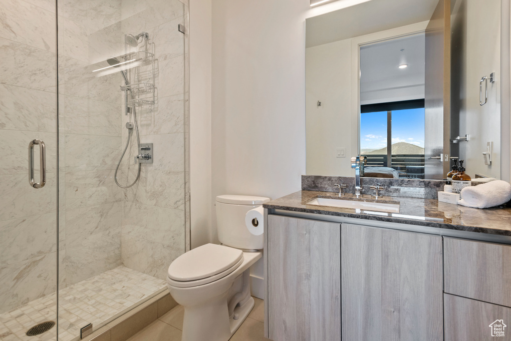 Bathroom with walk in shower, tile patterned floors, toilet, and vanity