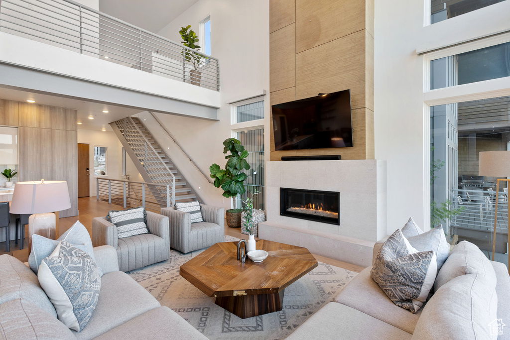 Living room with plenty of natural light, a fireplace, light hardwood / wood-style floors, and a high ceiling