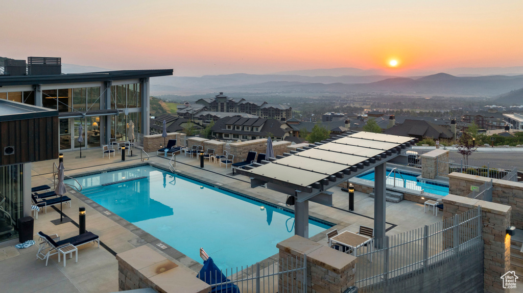 Pool at dusk featuring a patio area and a mountain view