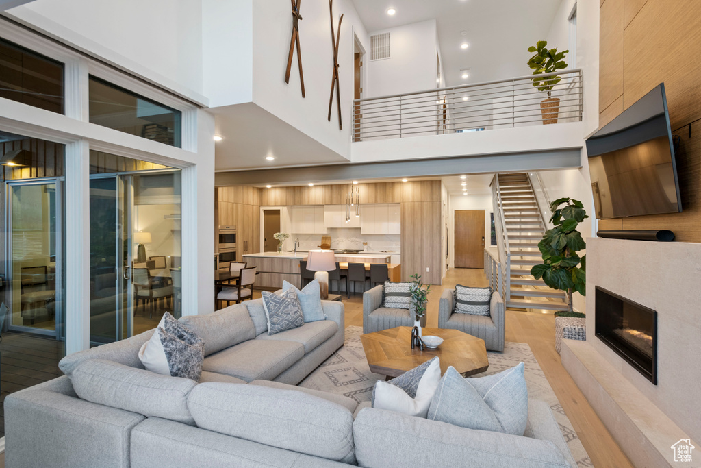 Living room with sink, a premium fireplace, light wood-type flooring, and a high ceiling