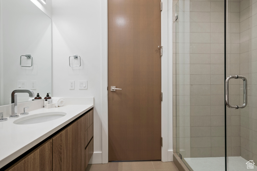 Bathroom with a shower with door, vanity, and tile patterned flooring