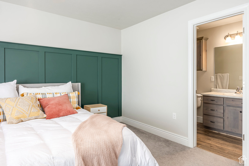 Bedroom with sink, light hardwood / wood-style flooring, and ensuite bathroom