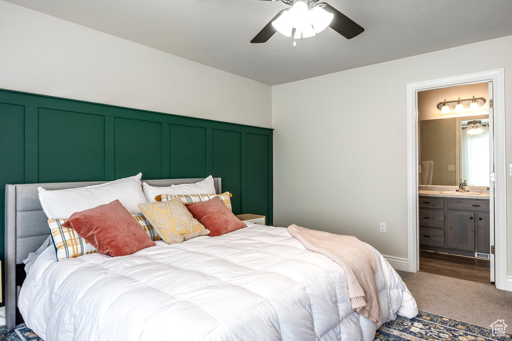 Carpeted bedroom featuring ensuite bath, sink, and ceiling fan