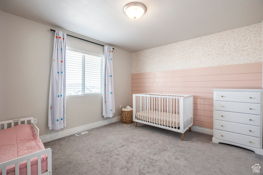 Bedroom featuring light carpet and a nursery area