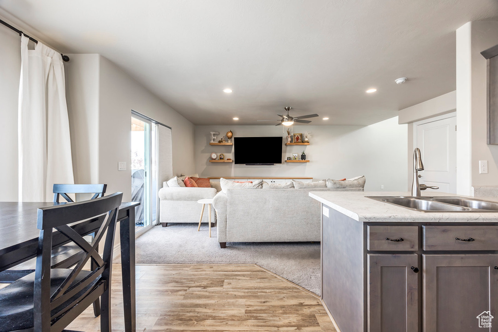 Kitchen featuring light stone counters, ceiling fan, light carpet, dark brown cabinetry, and sink