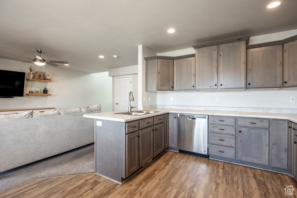 Kitchen featuring stainless steel dishwasher, ceiling fan, sink, kitchen peninsula, and dark wood-type flooring