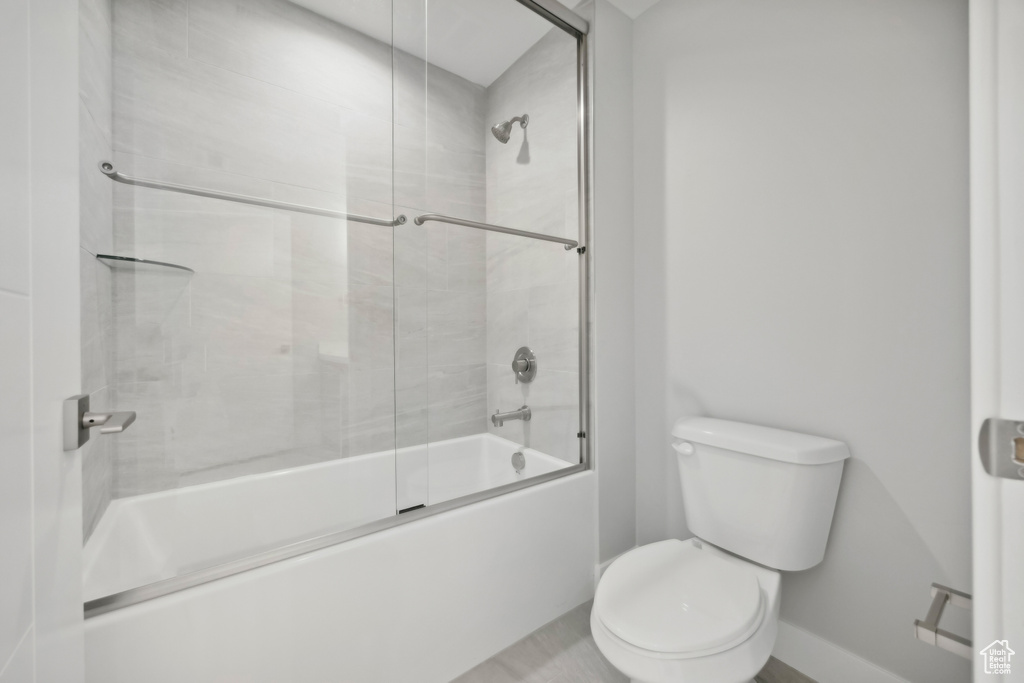 Bathroom with bath / shower combo with glass door and toilet