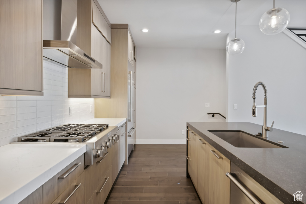 Kitchen featuring dark hardwood / wood-style flooring, decorative backsplash, stainless steel gas stovetop, wall chimney exhaust hood, and sink