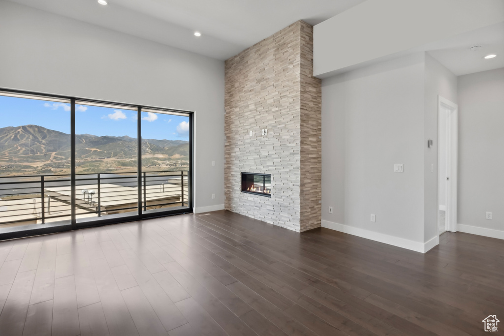 Unfurnished living room with a mountain view, a fireplace, hardwood / wood-style flooring, and a towering ceiling