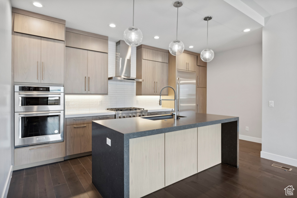 Kitchen featuring dark wood-type flooring, a kitchen island with sink, and wall chimney exhaust hood