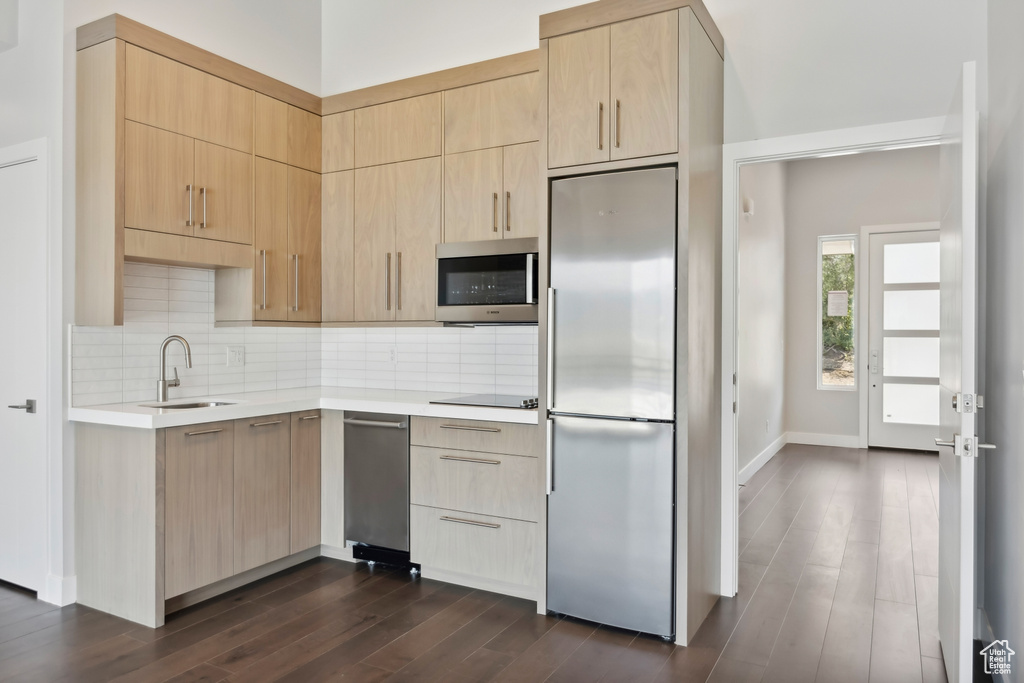 Kitchen featuring appliances with stainless steel finishes, tasteful backsplash, sink, light brown cabinets, and dark hardwood / wood-style floors