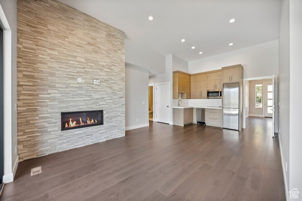 Unfurnished living room featuring dark hardwood / wood-style floors, sink, and a large fireplace