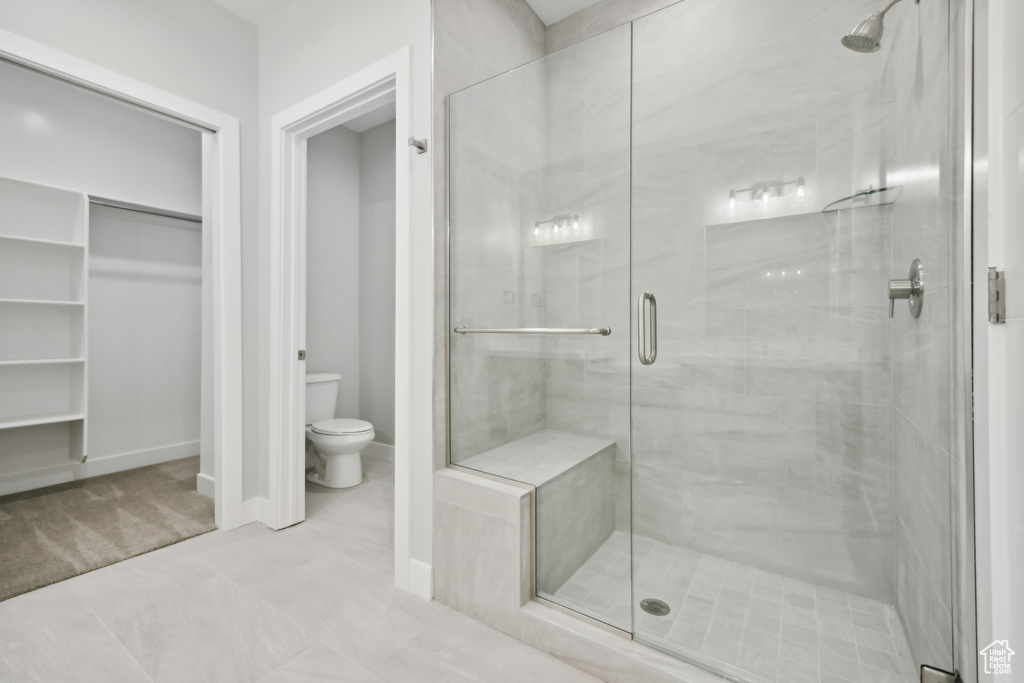 Bathroom with walk in shower, tile patterned floors, and toilet