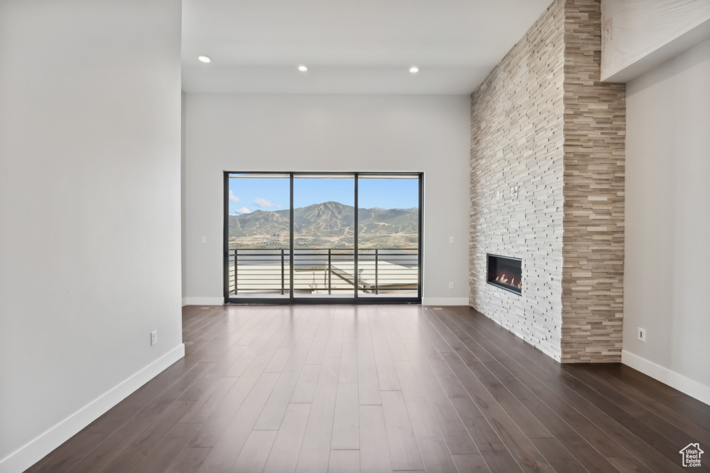 Unfurnished living room with a mountain view, dark hardwood / wood-style flooring, a fireplace, and a high ceiling