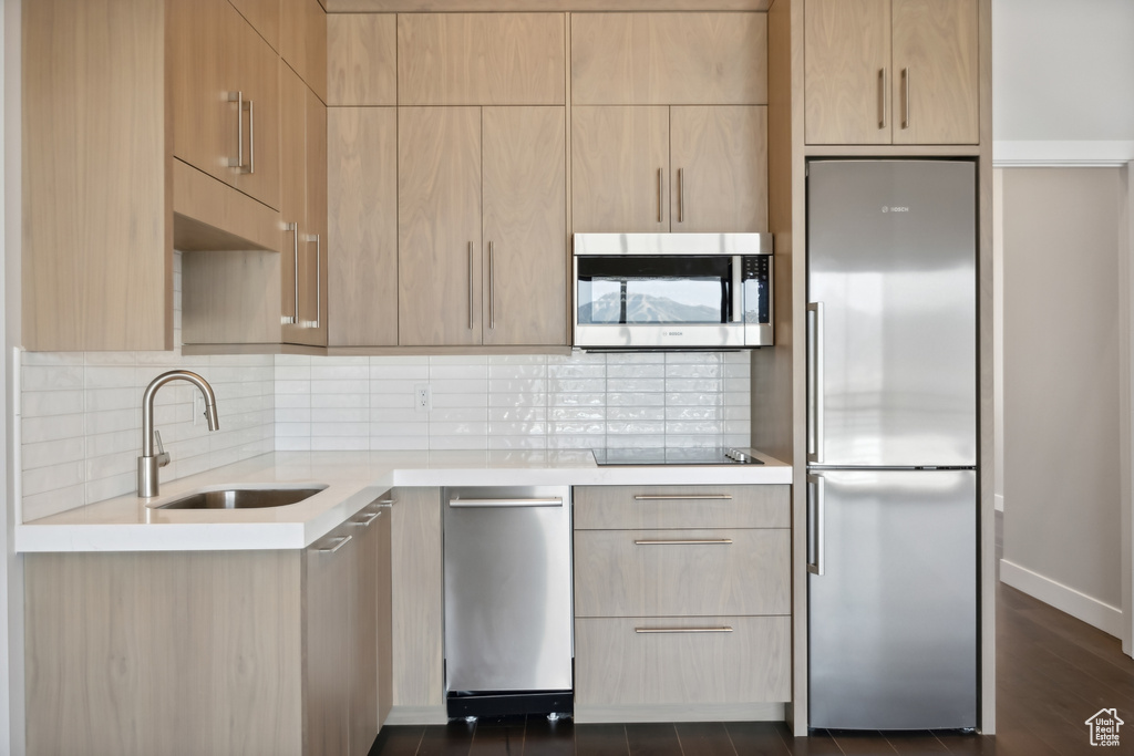 Kitchen featuring light brown cabinetry, stainless steel appliances, sink, dark hardwood / wood-style floors, and backsplash